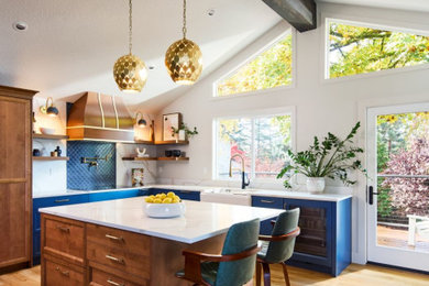 Example of a large transitional u-shaped medium tone wood floor and brown floor kitchen design in Portland with a farmhouse sink, recessed-panel cabinets, medium tone wood cabinets, quartz countertops, blue backsplash, an island and white countertops