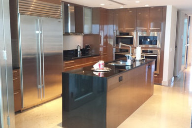 Inspiration for a large contemporary l-shaped marble floor eat-in kitchen remodel in Miami with an undermount sink, flat-panel cabinets, light wood cabinets, granite countertops, beige backsplash, glass sheet backsplash, stainless steel appliances and an island