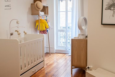Modelo de habitación de bebé niña actual de tamaño medio con paredes blancas y suelo de madera clara