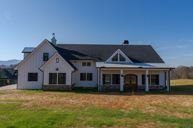 Foto della villa bianca country a un piano di medie dimensioni con rivestimento con lastre in cemento, tetto a capanna, copertura mista, tetto nero e pannelli e listelle di legno