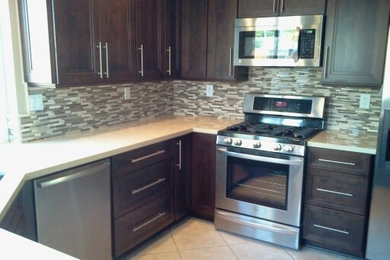 Example of a mid-sized trendy u-shaped ceramic tile enclosed kitchen design in Los Angeles with a double-bowl sink, dark wood cabinets, laminate countertops, multicolored backsplash, matchstick tile backsplash, stainless steel appliances, no island and recessed-panel cabinets