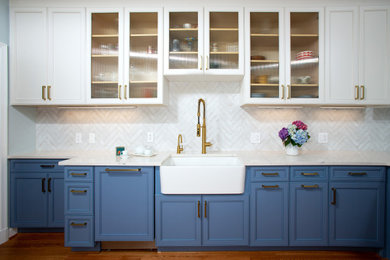 Wet bar - mid-sized traditional l-shaped medium tone wood floor and brown floor wet bar idea in DC Metro with glass-front cabinets, white cabinets, quartz countertops, white backsplash and white countertops