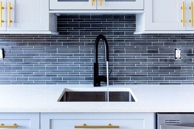 Enclosed kitchen - mid-sized transitional galley enclosed kitchen idea in New York with an undermount sink, shaker cabinets, white cabinets, quartz countertops, black backsplash, matchstick tile backsplash, stainless steel appliances and an island