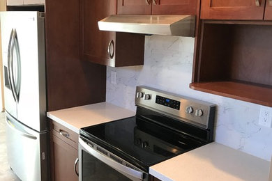 Eat-in kitchen - mid-sized traditional galley porcelain tile and gray floor eat-in kitchen idea in San Francisco with a double-bowl sink, flat-panel cabinets, dark wood cabinets, quartz countertops, white backsplash, porcelain backsplash, stainless steel appliances, no island and white countertops