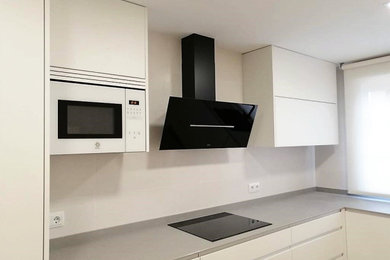 Foto de cocinas en L minimalista de tamaño medio cerrada con armarios con paneles lisos y puertas de armario blancas