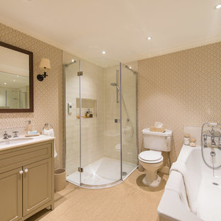 This is an example of a classic ensuite bathroom in Other with raised-panel cabinets, beige cabinets, a corner bath, a corner shower, a two-piece toilet, beige tiles, metro tiles, beige walls, a submerged sink, beige floors, a hinged door and white worktops.