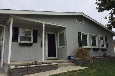 Mid-sized trendy gray one-story stucco gable roof photo in Los Angeles