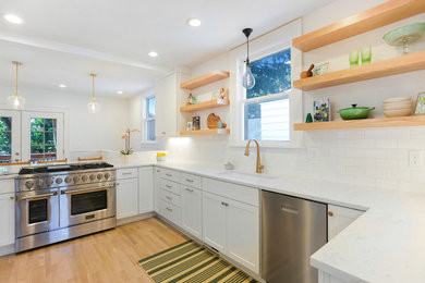 Mid-sized transitional l-shaped light wood floor enclosed kitchen photo in Portland with an undermount sink, shaker cabinets, white cabinets, quartz countertops, white backsplash, subway tile backsplash, stainless steel appliances, no island and white countertops