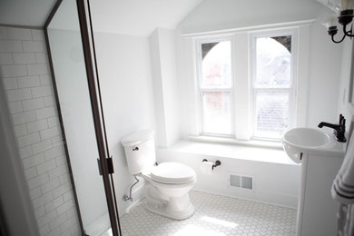 This is an example of a small transitional 3/4 bathroom in Kansas City with a wall-mount sink, flat-panel cabinets, white cabinets, a corner shower, white tile, ceramic floors, a two-piece toilet, white walls, a hinged shower door, subway tile and white floor.
