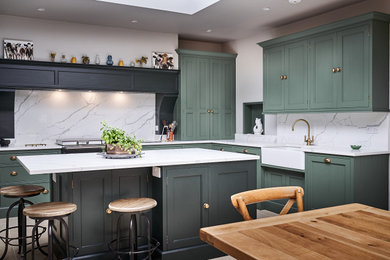 Transitional l-shaped eat-in kitchen in Other with a farmhouse sink, shaker cabinets, green cabinets, white splashback, stone slab splashback, with island and white benchtop.