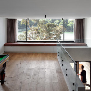 Immagine di un ampio soggiorno minimalista aperto con sala giochi, pareti bianche, parquet chiaro e pavimento marrone