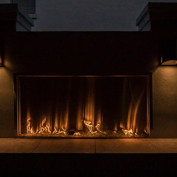 Walled-in outdoor covered lanai with custom fireplace and artificial greens