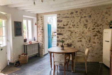 Idée de décoration pour une salle à manger ouverte sur le salon champêtre de taille moyenne avec un mur beige, un sol en carrelage de céramique, aucune cheminée, un sol noir et poutres apparentes.