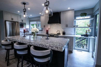 Inspiration for a mid-sized contemporary vinyl floor and gray floor kitchen remodel in Vancouver with a double-bowl sink, shaker cabinets, white cabinets, quartz countertops, white backsplash, quartz backsplash, stainless steel appliances and white countertops