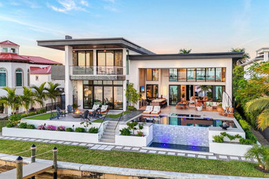 Trendy white two-story stucco exterior home photo in Miami with a gray roof