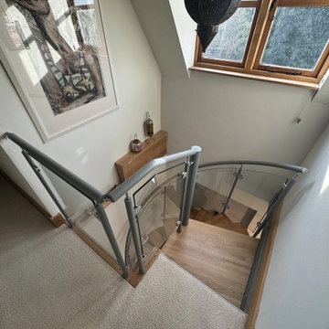 Lovely cottage spiral staircase with oak treads and curved glass railing