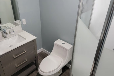 Small elegant kids' vinyl floor, gray floor and single-sink corner shower photo in Calgary with flat-panel cabinets, gray cabinets, a one-piece toilet, gray walls, an integrated sink, a hinged shower door, white countertops and a freestanding vanity