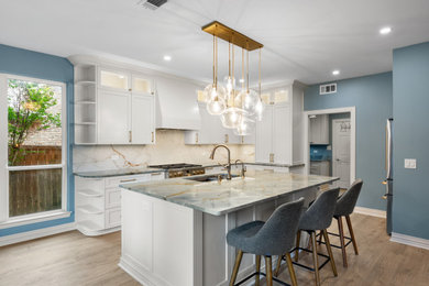 Inspiration for a transitional light wood floor and brown floor kitchen remodel in Dallas with an undermount sink, shaker cabinets, white cabinets, quartzite countertops, multicolored backsplash, quartz backsplash, stainless steel appliances, an island and multicolored countertops