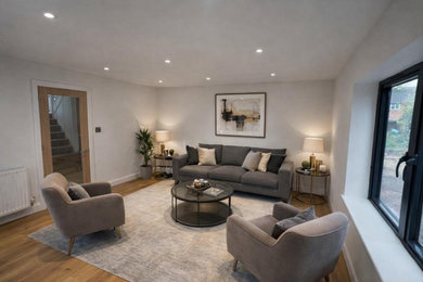 Medium sized modern living room in Sussex with white walls and brown floors.