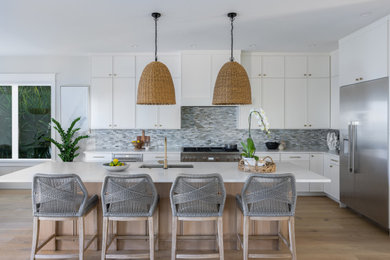 Beach style l-shaped eat-in kitchen photo in Tampa with a drop-in sink, white cabinets, stainless steel appliances, an island and white countertops