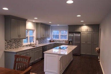 Example of a large trendy l-shaped dark wood floor eat-in kitchen design in Other with an undermount sink, recessed-panel cabinets, gray cabinets, quartz countertops, multicolored backsplash, glass tile backsplash, stainless steel appliances and an island