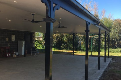 Photo of a large backyard verandah in Other with concrete slab and a roof extension.