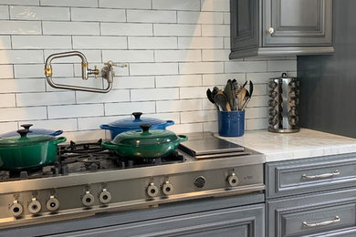 Kitchen - transitional kitchen idea in Little Rock with marble countertops and an island