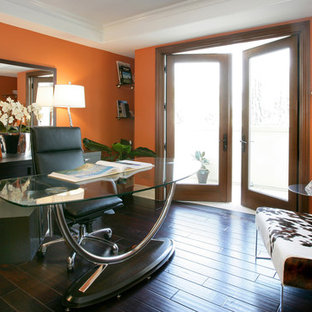 Photo of a large modern home office and library in Los Angeles with orange walls, dark hardwood flooring, no fireplace and a freestanding desk.
