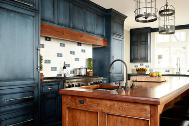 Photo of a traditional kitchen in New York with wood benchtops, recessed-panel cabinets, blue cabinets and panelled appliances.