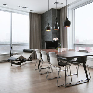 Inredning av en modern matplats med öppen planlösning, med ljust trägolv, en spiselkrans i betong och en öppen hörnspis