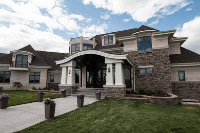 Large elegant beige two-story stone house exterior photo in Detroit with a hip roof and a shingle roof