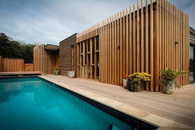 This is an example of a mid-sized contemporary custom-shaped pool in Auckland with decking.