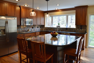 This is an example of an arts and crafts u-shaped eat-in kitchen in Denver with an undermount sink, recessed-panel cabinets, medium wood cabinets, granite benchtops, multi-coloured splashback, stainless steel appliances, with island and slate splashback.