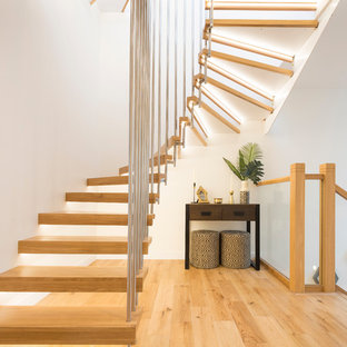 Inspiration for a contemporary wood curved metal railing staircase in London with open risers.