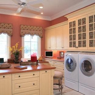 This is an example of a traditional utility room in Miami with pink walls and white cabinets.
