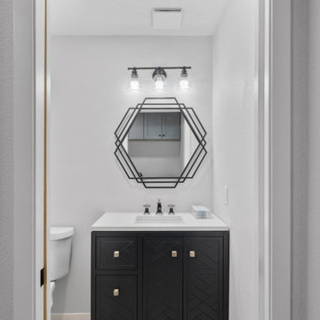 Stylish Half Bath Remodel with Black Vanity and Geometric Mirror