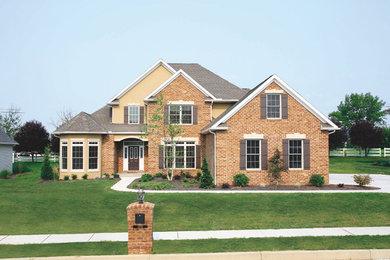 Large elegant yellow two-story brick exterior home photo in Other with a clipped gable roof
