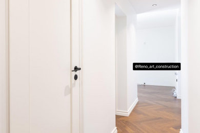 Inspiration for a large timeless medium tone wood floor and brown floor hallway remodel in New York with white walls