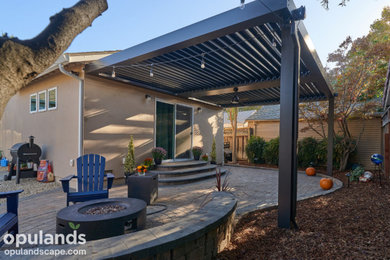 Backyard concrete paver patio photo in San Francisco with a pergola