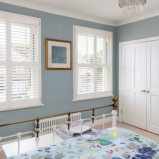 Small modern master bedroom in London with blue walls and carpet.