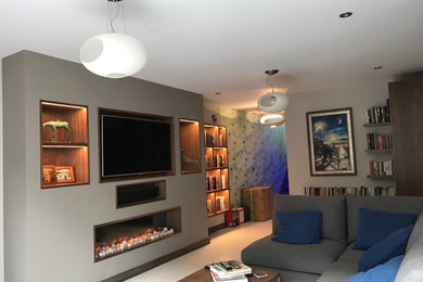 Design ideas for a medium sized modern enclosed living room in London with grey walls, a hanging fireplace and a built-in media unit.