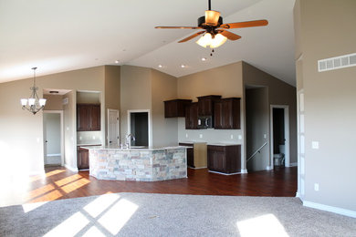 Mid-sized elegant l-shaped dark wood floor open concept kitchen photo in Wichita with an undermount sink, raised-panel cabinets, dark wood cabinets, quartz countertops, stainless steel appliances and an island