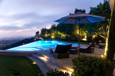 Trendy backyard stone and custom-shaped infinity pool photo in Orange County
