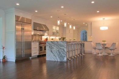 Inspiration for a large contemporary l-shaped dark wood floor enclosed kitchen remodel in New York with white cabinets, white backsplash, stainless steel appliances, an island, a double-bowl sink, shaker cabinets, marble countertops and subway tile backsplash