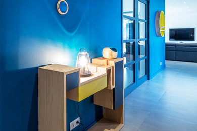 Cette image montre un grand hall d'entrée design avec un mur bleu et une porte grise.