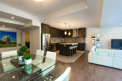 Inspiration for a mid-sized contemporary l-shaped medium tone wood floor open concept kitchen remodel in Calgary with an undermount sink, dark wood cabinets, granite countertops, stainless steel appliances and an island