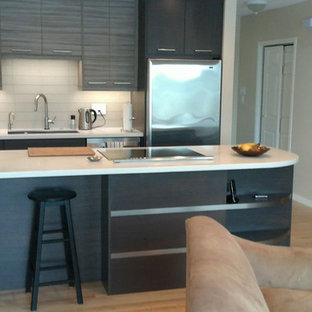 Неиссякаемый источник вдохновения для домашнего уюта: параллельная кухня среднего размера в стиле модернизм с кладовкой, врезной раковиной, плоскими фасадами, темными деревянными фасадами, столешницей из кварцита, серым фартуком, фартуком из стеклянной плитки, техникой из нержавеющей стали, светлым паркетным полом, островом и желтым полом