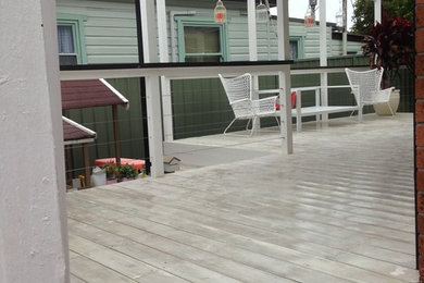This is an example of a large contemporary backyard deck in Wollongong with a pergola.