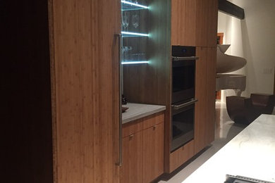 Inspiration for a large contemporary u-shaped concrete floor eat-in kitchen remodel in Santa Barbara with a farmhouse sink, flat-panel cabinets, brown cabinets, quartzite countertops, stainless steel appliances and two islands
