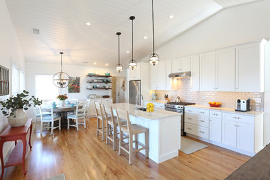 Beach style light wood floor and beige floor eat-in kitchen photo in Portland Maine with an undermount sink, white cabinets, quartz countertops, white backsplash, stainless steel appliances, an island, shaker cabinets and subway tile backsplash